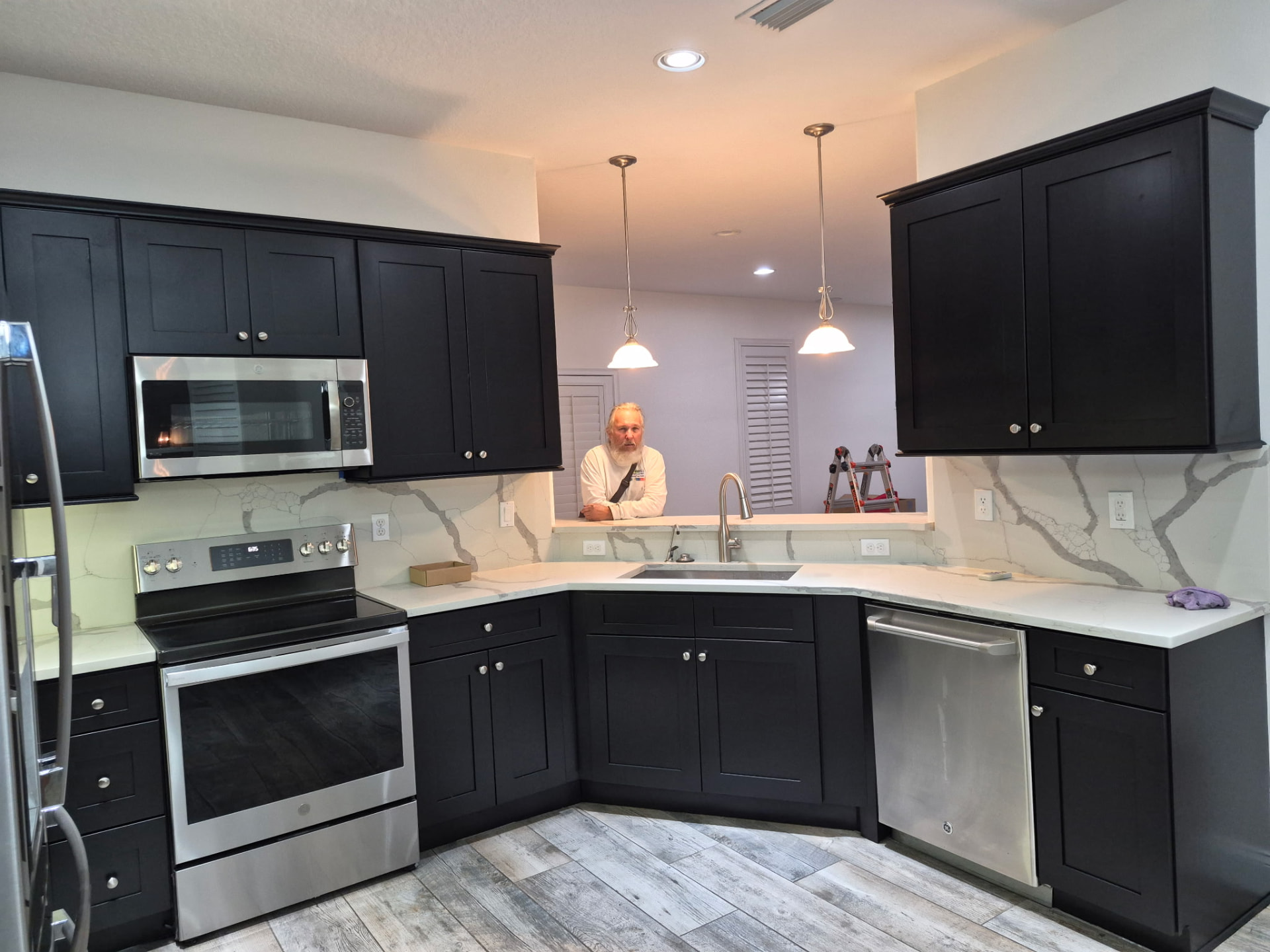 Remodeled kitchen with freshly painted dark cabinets and white countertops