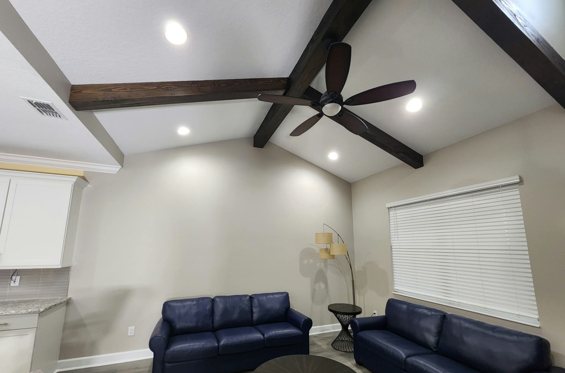 Living room with fresh greige walls, white vaulted ceiling and stained wood beams