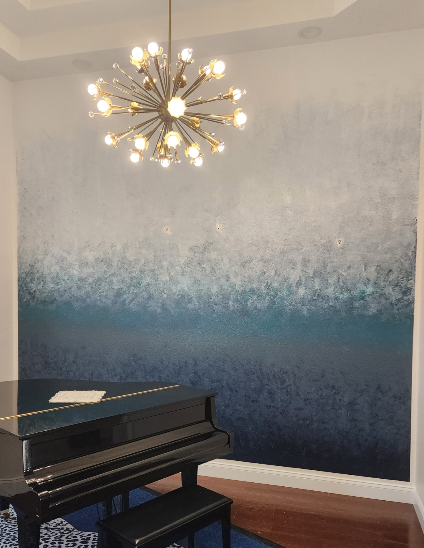 Dining room accent wall with a textured blue ombre finish beneath a brass chandelier